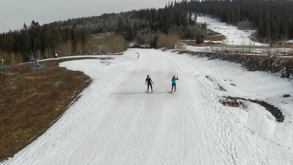 Aerial View Two Female Skiers, Walking on Skis in a Mountainous Area, Warm Weather and the Snow