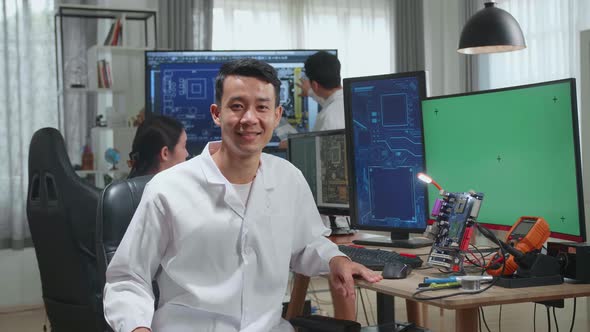 Asian Man Smiling Charmingly Looking At Camera. Young Intelligent Male Scientist Working In Office