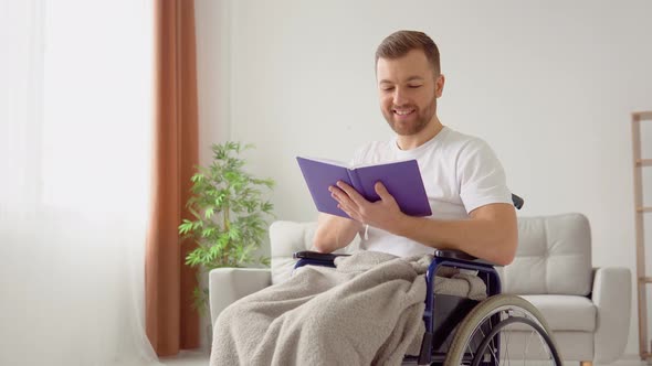 Cheerful Happy Disabled Person Reading a Book in a Wheelchair