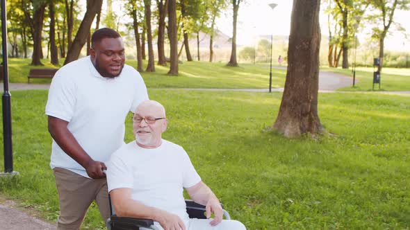 African-American caregiver and old disabled man in a wheelchair. Nurse and patient.