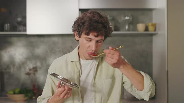 Man Enjoying Delicious Meal While Trying It From Spoon