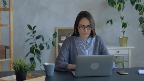 Beautiful Woman in Eyeglasses Work on Laptop in Office