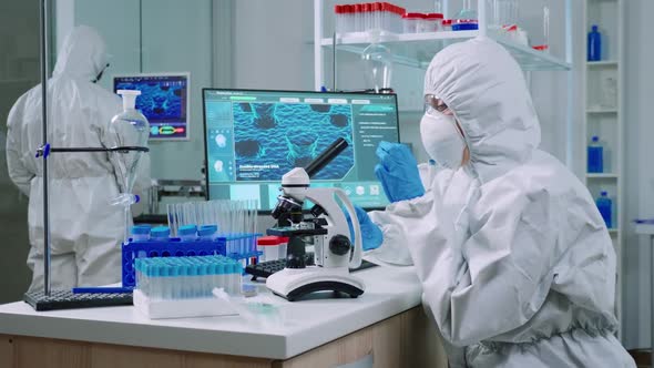 Chemist in Protection Suit Typing on Pc and Analyzing Virus Sample alt