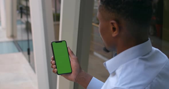 Overshoulder View of Afro American Businessman Holding Smartphone in His Hand and Looking at Screen