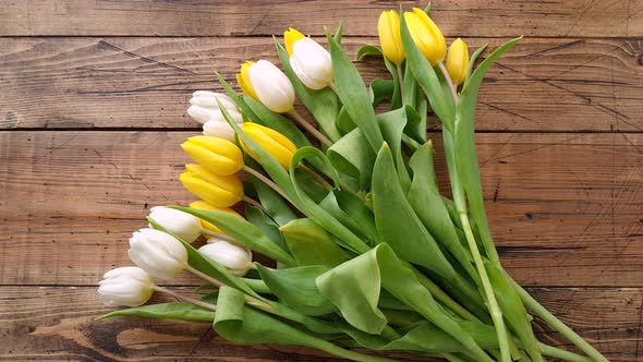 Take yellow and white tulips bouquet from a wooden table top view