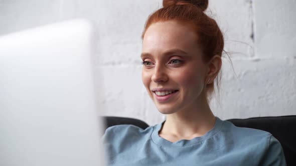 Close-up of Face of Redhead Young Businesswoman Working on Modern Laptop Computer.