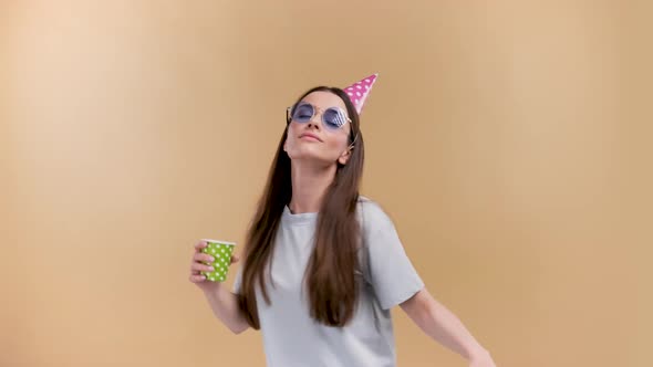 A Girl in Casual Clothes Dancing Wearing a Horn Hat Glasses and Holding a Glass