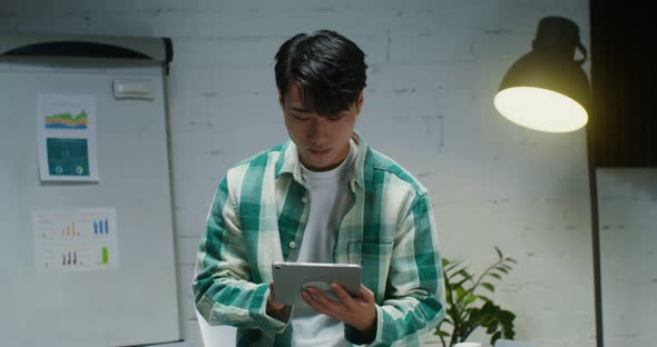 Young Asian Man Smiling Looking at Camera While Standing with Tablet in Office