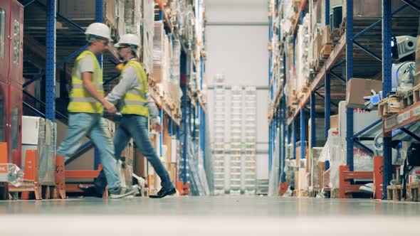 Warehouse Workers and Robot Moving Along the Aisle