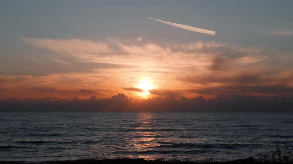 Orange Cloudy sunset at mediterranean sea with sun reflection on water. Sunset concept