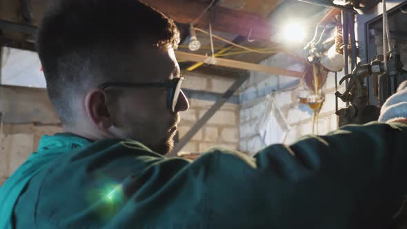 Young Repairman in Protective Glasses Examining Vehicle Detail at Garage