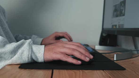 Closeup of a Man's Hands Controlling a Computer Program Using a Mouse and Keyboard in a Home Office