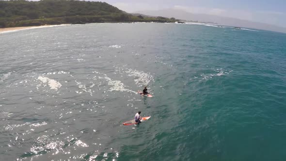 Aerial view of two men sup stand-up paddleboard surfing in Hawaii.