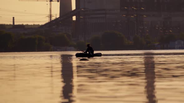 Fisherman in a boat with fishing rods in the evening. Man in hat floating in a boat and fishing 