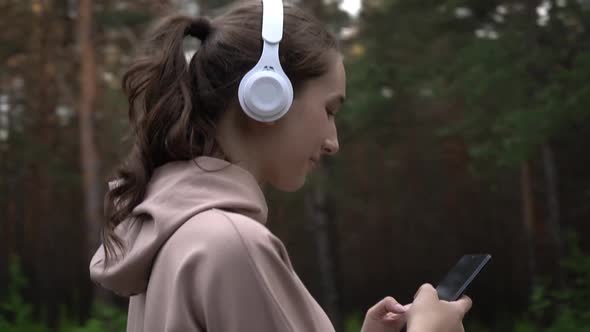 A Girl with Headphones and a Smartphone on a Jog