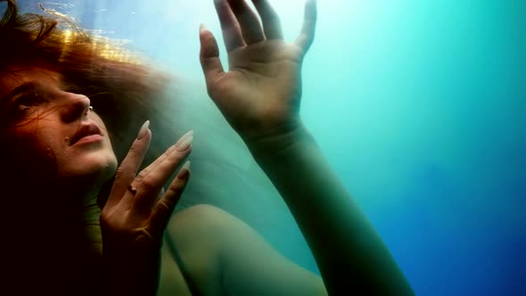 Dreamy Underwater Shot with Beautiful Enigmatic Lady Floating in Blue Water Fairytale and Mystery