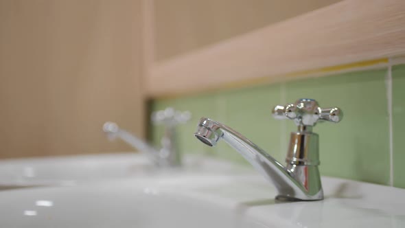 Shiny Metal Faucet with Lever on Sink in Public Restroom