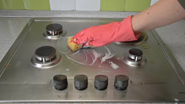 Housewife in Gloves Washes the Gas Stove in Kitchen with a Washcloth and Foam