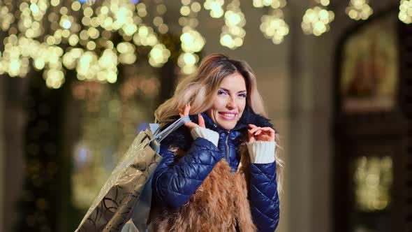 Portrait Smiling Luxury Woman with Shopping Bags Surrounded By Christmas Yellow Brightness Lights