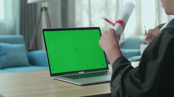 Over The Shoulder Of Man Showing A University Certificate To Laptop Computer With Green Screen