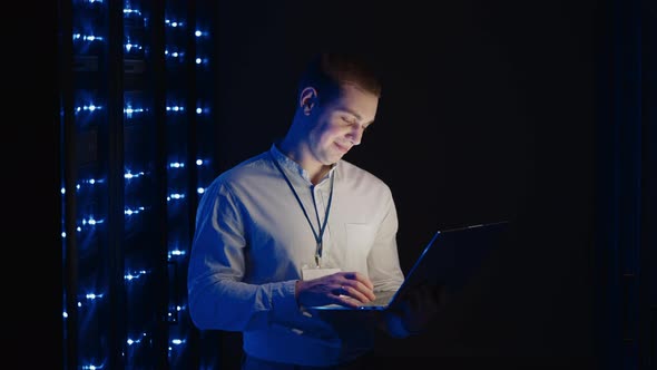 A Young Technician with a Laptop Deals with the Problem of the Server and Raises the Server Broken