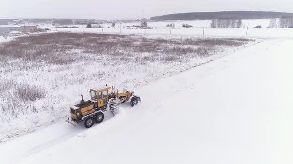 Aerial view of Snowblower Grader Clears Snow Covered Country Road  next to the forest 16