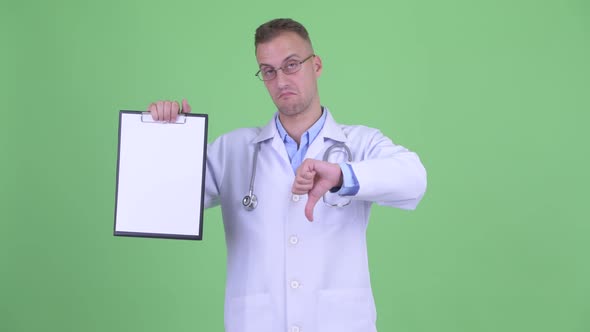 Stressed Man Doctor Showing Clipboard and Giving Thumbs Down