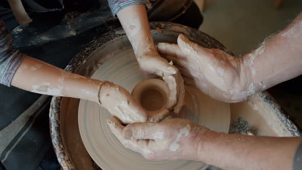 Top View of Boy and Man's Hands Shaping Clay Into Pot Working in Pottery Studio