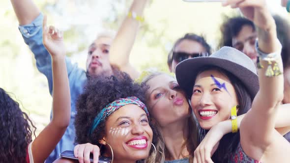 Friends taking selfie with mobile phone at music festival