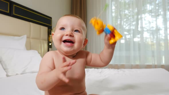 Little Kid with Toy in Hands Sitting on Sofa Smiling. Sweet Child Playing at Home in Cosy Bedroom