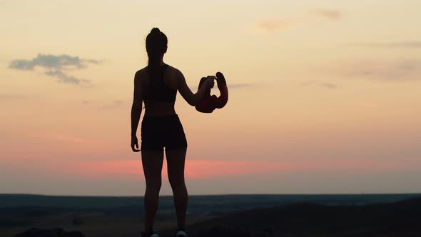 Silhouette of an athlete in a tracksuit stands against the background of the sunset