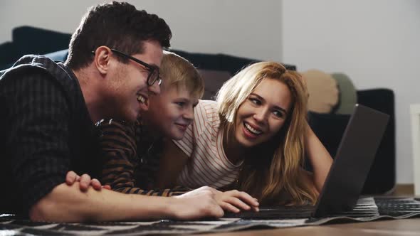 Smiling Family Looking at Computer Screen and Enjoying Watching Funny Social Media Video. Happy