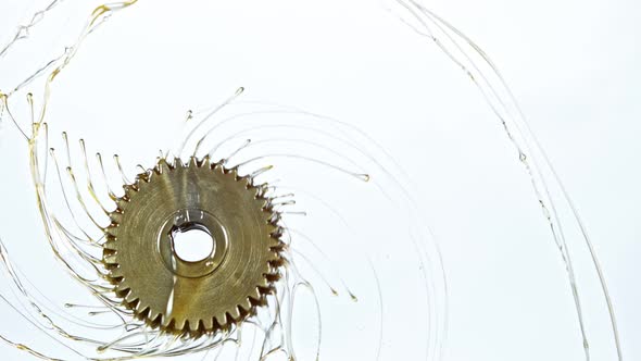 Super Slow Motion Shot of Rotating and Splashing Metal Cogwheel on White Background at 1000 Fps