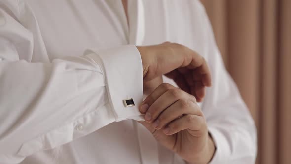 Handsome Groom Man Dresses in Wedding Morning and Fixes His Cufflink Buttons on a White Shirt Sleeve