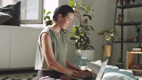 Woman Sitting in Lotus Pose and Using Laptop at Home