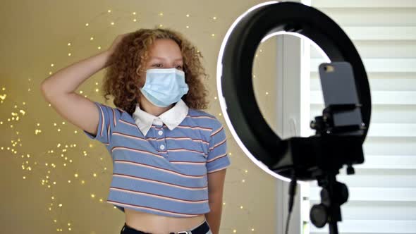 Cheerful Teen Girl Dancing at Camera in a Medical Mask Filming Video Creating Her Trendy Content on