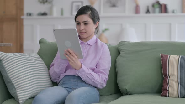 Indian Woman Celebrating Success on Tablet on Sofa