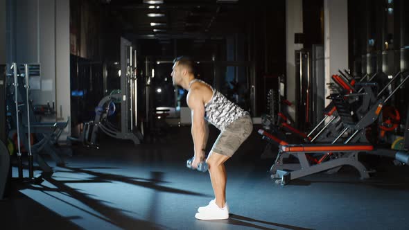 Athletic Muscular Man Works Out and Sit Up With Dumbbells in Gym