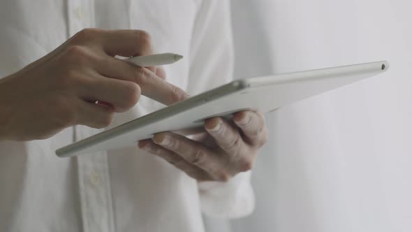 Close-up Asian businessman signing a digital contract on a tablet using a stylus pen.