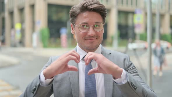 Middle Aged Businessman Showing Heart Sign by Hand