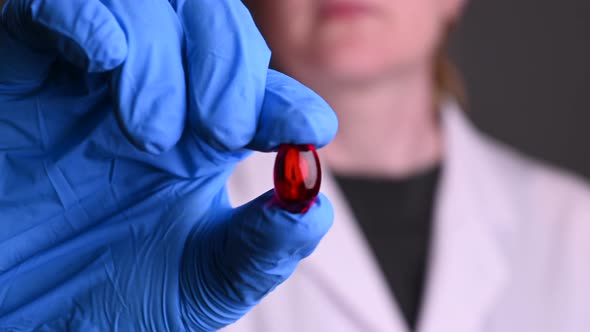 A Female Doctor Shows To the Camera a Red Tablet Close-up, the Antiviral Drug