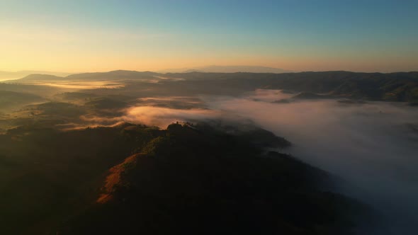 4K aerial view over a misty mountainous area. The great golden sun in the morning