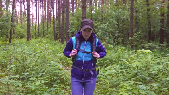 Portrait of a Girl with a Tourist Backpack Walking Through the Woods