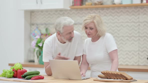 Loving Old Couple Working on Laptop in Kitchen