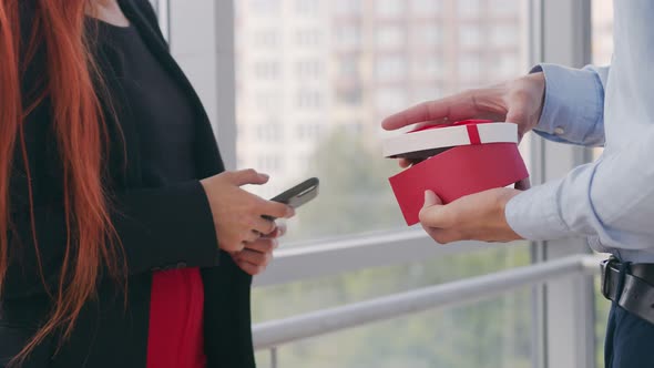 Close Up Man Opening a Box with a Gift for a Girl A Woman Who Speaks on the Phone Receives a Gift