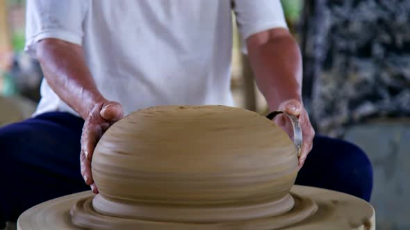 Closeup Asian Potter Grinds Big Ceramic Pot with Metal Ring