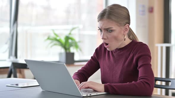 Young Woman Reacting to Loss on Laptop in Office