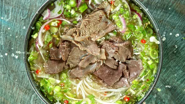 Super Slow Motion Detail Shot of Sliced Beef Falling Into Pho Soup at 1000 Fps.