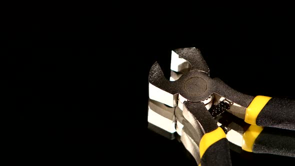 Part of Wire Cutters with Yellow, Gray Handle on Black, Reflection, Rotation