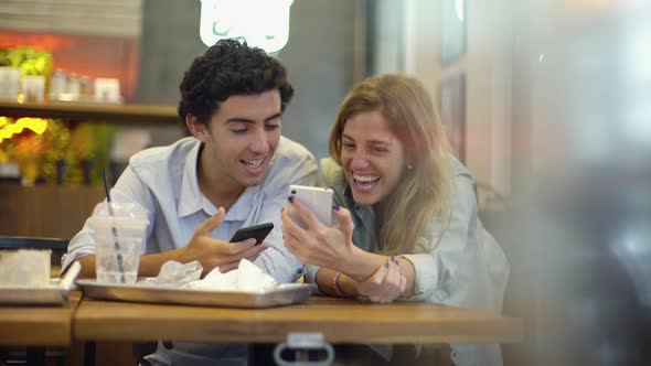 Couple using smartphones at fast food restaurant